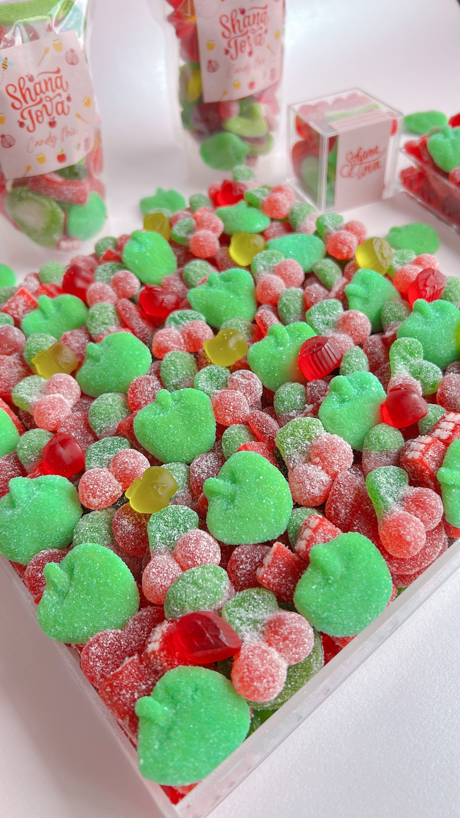 Assorted gummy candies including green and red with green apple strawberry and cherry flavours