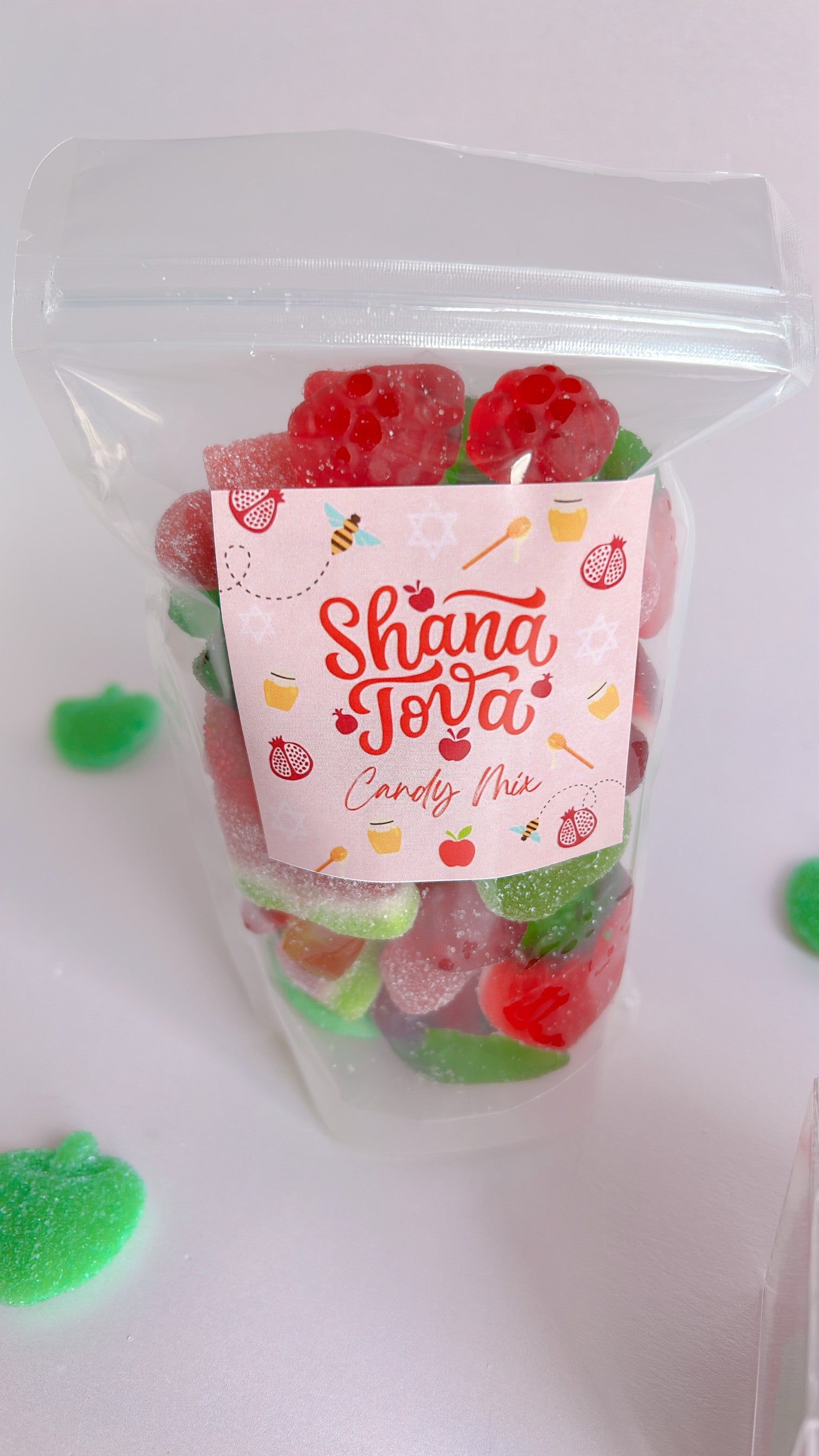 Packaged candy with a Shana Tova label filled with red and green themed candy
