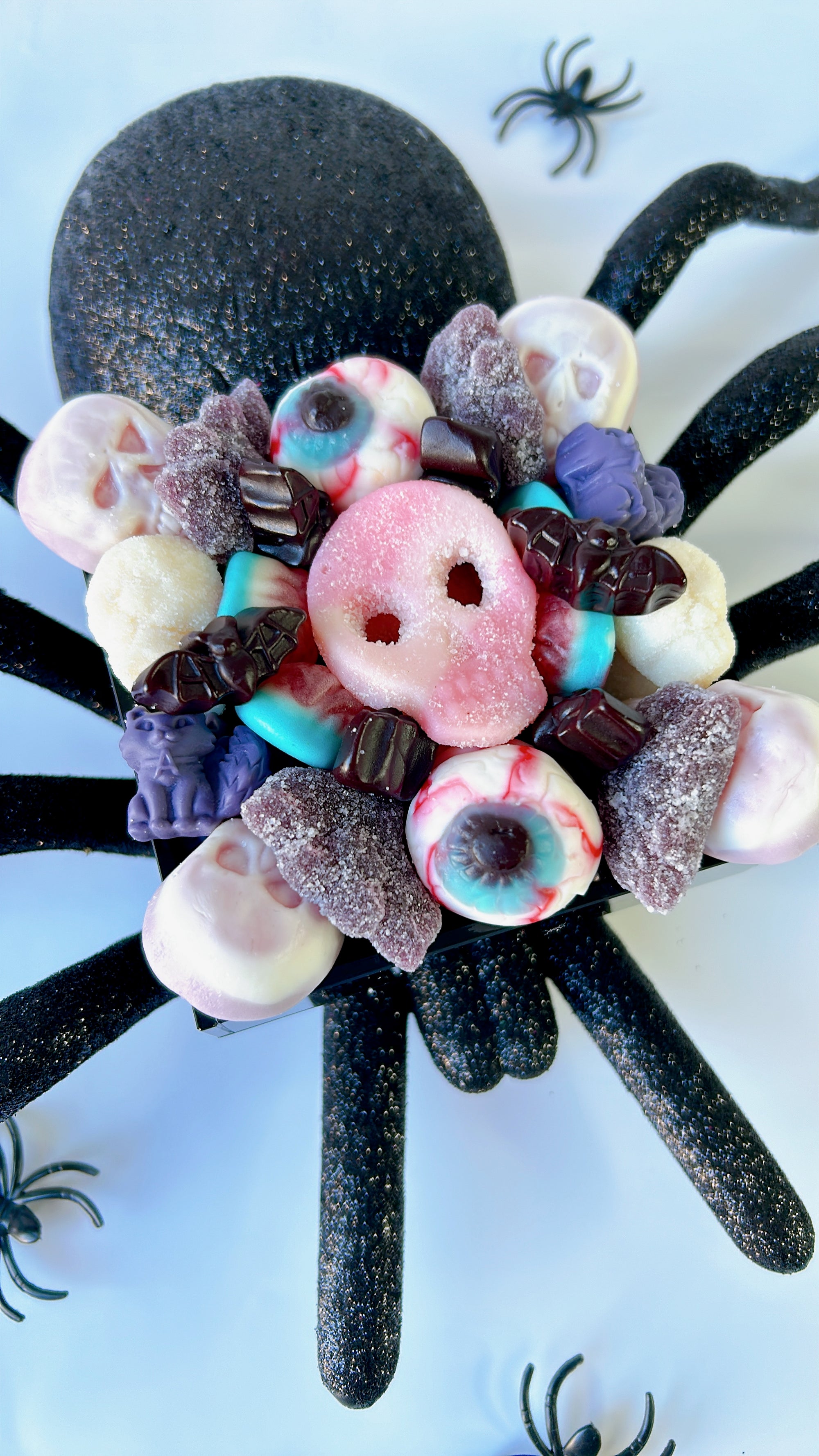 Candy tray with halloween-themed candy resting on top of a plastic spider used as a prop for halloween