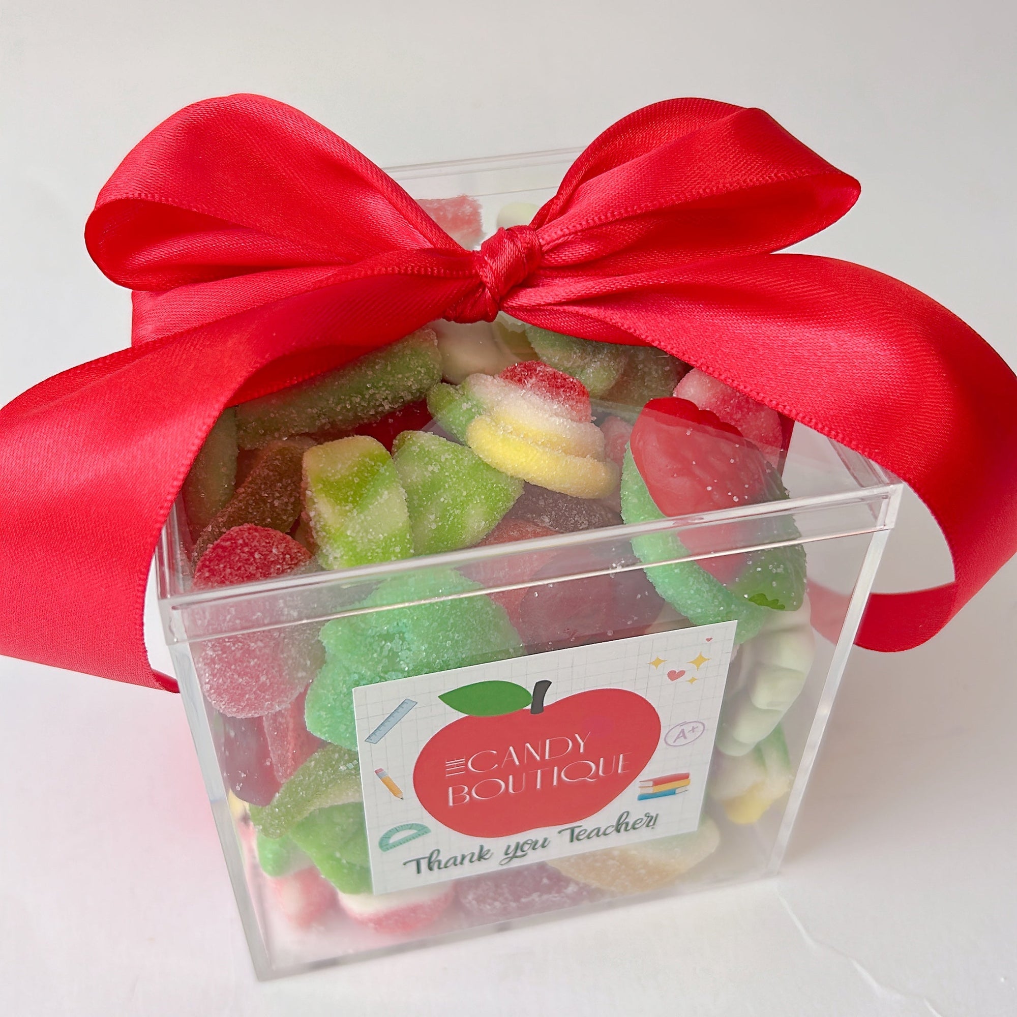 Clear container of gummy candies with a red ribbon and a label for teacher gift